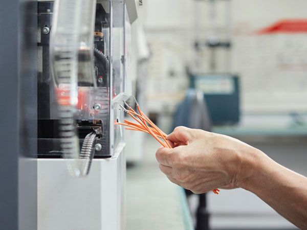 Eine Nahaufnahme einer Hand, die Drähte in eine Maschine einführt.